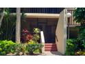 Close-up of a condo entrance with a screen door, tropical plants, and stairs at 6462 Wild Oak Bay Blvd # 245, Bradenton, FL 34210