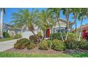 Charming home featuring a red front door and lush tropical landscaping with mature palms and flowering shrubs at 8019 Indigo Ridge Ter, Bradenton, FL 34201