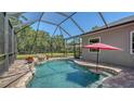 Backyard pool featuring a rock waterfall, surrounding patio, screened-in enclosure, and lush landscaping at 8019 Indigo Ridge Ter, Bradenton, FL 34201