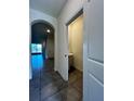 Hallway with tile flooring leading to an archway and a half-bath with pedestal sink at 8864 Milestone Dr, Sarasota, FL 34238