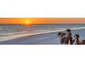Scenic view of a serene beach at sunset, featuring calm waves and swaying palm trees along the sandy shore at 2525 Gulf Of Mexico Dr # 3F, Longboat Key, FL 34228