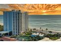 Coastal condo building with beach access, tennis court, and pool overlooking the ocean during a vibrant sunset at 2525 Gulf Of Mexico Dr # 3F, Longboat Key, FL 34228