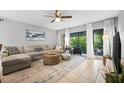 Bright living room featuring a large sectional sofa, stylish rug, ceiling fan, and sliding glass doors at 2950 Clark Rd # 113, Sarasota, FL 34231