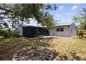 A spacious backyard featuring a screened-in porch, mature trees, and a firepit at 3505 27Th W Ave, Bradenton, FL 34205
