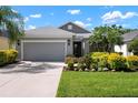 Charming single-story home with a well-manicured lawn, lush landscaping, and a gray two-car garage at 4814 Lake Breeze Ter, Sarasota, FL 34243
