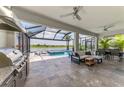 The outdoor living space boasts a barbecue, comfortable seating, and a view of the screened-in pool and lake at 6252 Winding Pine Dr, Nokomis, FL 34275