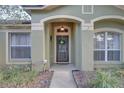 Close up of a front door with glass panels, decorative wreath, and sidelight windows at 12805 Raysbrook Dr, Riverview, FL 33569