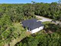 A modern home with a new roof is captured in an aerial view, surrounded by lush greenery and serene landscapes at 14009 Daniels Ave, Port Charlotte, FL 33953
