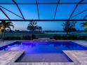 Inviting screened-in pool with waterfall feature, lush landscaping and tranquil views of the golf course at twilight at 15037 Montello Way, Lakewood Ranch, FL 34211