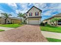 Inviting two-story home featuring a brick driveway, lush lawn, and manicured landscaping at 2084 La Palma Ave, Port Charlotte, FL 33953