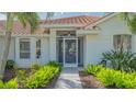Close-up of front door with decorative security screen and lush green landscaping framing the walkway at 2115 Timucua Trl, Nokomis, FL 34275