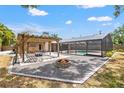 Outdoor living space with a stone firepit, pergola, and access to a screened pool area at 2778 Greendale Dr, Sarasota, FL 34232