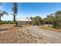 Exterior view of the home showing the front yard and long gravel driveway at 28706 102Nd E Dr, Myakka City, FL 34251