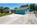 Exterior shot showcasing the teal home with a vibrant garage door and extended driveway space at 4219 Berkshire Dr, Sarasota, FL 34241