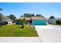 Bright teal home with manicured lawn, palm tree, and blue garage door under a clear sky at 4219 Berkshire Dr, Sarasota, FL 34241