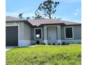 Close-up of a charming single-story home featuring a well-maintained lawn, gray exterior paint, and a white front door at 5115 Foxhall Rd, North Port, FL 34288