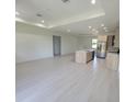 Spacious living room connects to an open kitchen with an island, modern lighting, and sleek flooring at 5115 Foxhall Rd, North Port, FL 34288