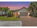 Beautiful single-Gathering home featuring a tile roof, two-car garage, brick paver driveway, and lush landscaping at twilight at 5388 Bartolomeo St, Sarasota, FL 34238