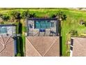 Aerial view of a screened pool with brick paver patio and lounge chairs, surrounded by tropical landscaping at 5388 Bartolomeo St, Sarasota, FL 34238