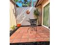 Enclosed brick-paved patio features a sunny sunburst wall hanging, lush plants, and a small table with chairs at 5657 Westwind Ln, Sarasota, FL 34231