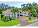 An elegant single-story house with a tiled roof, circular driveway and verdant landscaping at 6620 Saint James Xing, University Park, FL 34201
