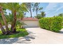 A well-maintained two-car garage with palm trees and tropical foliage in a landscaped yard at 7639 Fairway Woods Dr # 605, Sarasota, FL 34238