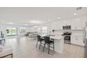Open-concept kitchen showcases stainless appliances, white cabinets, and an island with bar stools; open to living areas at 9725 Last Light Gln, Parrish, FL 34219