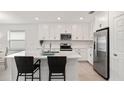 Stylish kitchen features white cabinets, stainless steel appliances, and a spacious island with bar stool seating at 9725 Last Light Gln, Parrish, FL 34219