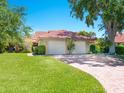 Charming home featuring a terracotta roof, two-car garage, well-manicured lawn, and mature trees at 1720 Kestral Park S Way # 49, Sarasota, FL 34231