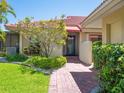 Inviting front entrance with a brick pathway, mature bushes, and terracotta roof at 1720 Kestral Park S Way # 49, Sarasota, FL 34231