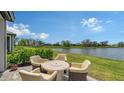 Backyard patio with outdoor seating offers serene lakeside views in a landscaped setting at 17946 Cherished Loop, Bradenton, FL 34211