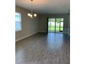 A spacious living room with wood tile flooring and sliding glass doors to the lanai at 240 Ibiza Loop, Venice, FL 34292