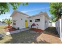 Charming home features a yellow front door, modern lighting fixtures, and professionally landscaped front yard at 3090 6Th St, Sarasota, FL 34237