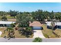 An aerial view of a single-story home with tile roof surrounded by lush greenery and neighboring houses at 3336 Pembrook Dr, Sarasota, FL 34239