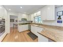 Well-lit kitchen featuring white cabinets, granite countertops, and stainless steel appliances, alongside modern fixtures at 3336 Pembrook Dr, Sarasota, FL 34239