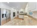Bright kitchen with white cabinetry, stainless steel appliances, and stone countertops with a view to hallway at 3336 Pembrook Dr, Sarasota, FL 34239