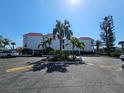 Well-maintained condo building featuring palm trees, lush greenery, and ample parking space on a sunny day at 3805 E Bay Dr # 302, Holmes Beach, FL 34217