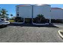 White condo building at 3805 with parking area and palm trees at 3805 E Bay Dr # 302, Holmes Beach, FL 34217