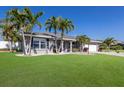 Well-maintained gray home featuring lush lawn, complemented by swaying palm trees and white rock landscaping at 3889 Canopy Way, Sarasota, FL 34235
