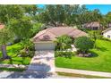 Exterior elevation with lush landscaping, mature trees, and a tile roof at 4356 Highland Oaks Cir # 3, Sarasota, FL 34235