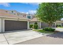 View of the townhouse featuring a brown garage door, well-maintained landscaping, and a charming exterior at 5346 Neil Dr, St Petersburg, FL 33714
