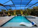 This screened-in pool features a lounge, spa, waterfall, outdoor kitchen, dining, and a basketball hoop at 603 165Th E St, Bradenton, FL 34212