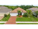 Aerial view of a well-maintained single-story home with lush landscaping and a brick driveway at 1034 Buttercup Gln, Bradenton, FL 34212