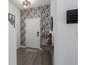 Inviting entryway with stylish wallpaper, modern light fixture, and elegant decor at 10464 Ladybug Cv, Parrish, FL 34219