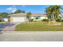 Well-maintained home featuring a stone facade garage, lush lawn, and mature palm trees in desirable area at 1104 76Th Nw St, Bradenton, FL 34209