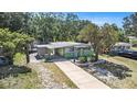 Quaint home with a light-green and white exterior, featuring a convenient carport, mature trees and long driveway at 1417 14Th E St, Bradenton, FL 34208