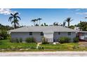 Charming single-story home featuring a clean design, gray siding, and vibrant landscaping with tropical foliage at 7030 Lois Ave, Longboat Key, FL 34228