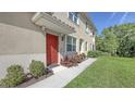 Attractive red front door entrance with stylish landscaping and a covered porch at 8352 Enclave Way # 104, Sarasota, FL 34243