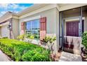 Inviting home featuring a screened front entrance, manicured shrubs, and accent shutters at 9052 41St E St, Parrish, FL 34219
