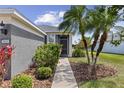 The front entrance features a gray exterior, lush landscaping, and a well-lit walkway leading to the front door at 9840 50Th Street E Cir, Parrish, FL 34219
